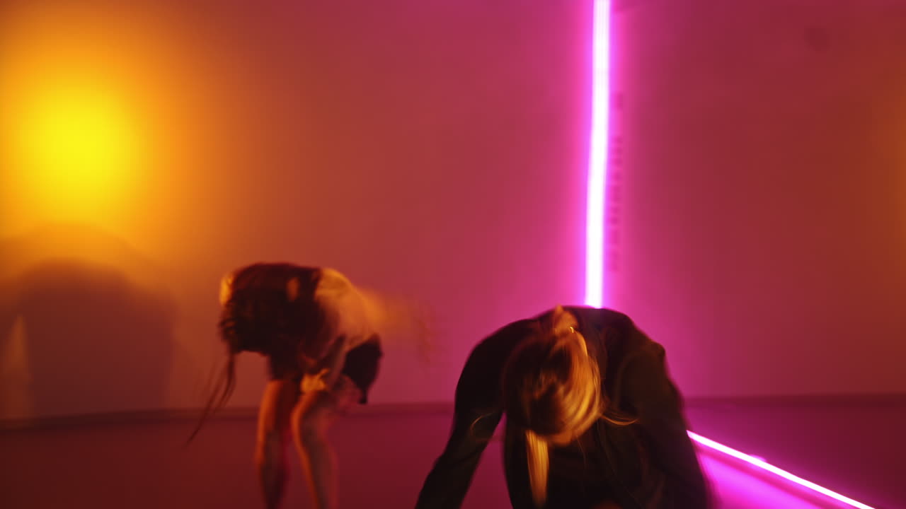 Three female dancers performing contemporary style dance in the studio. Team of dancers in the room with pink light.