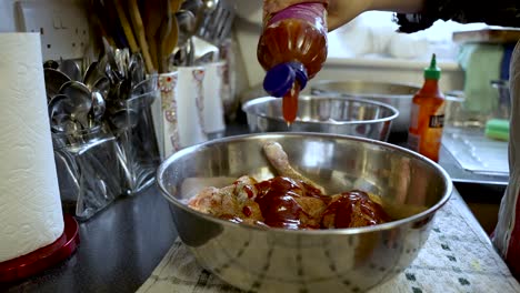 Pouring-sweet-and-sour-sauce-on-chicken-in-bowl,-kitchen-backdrop,-slow-motion-shot