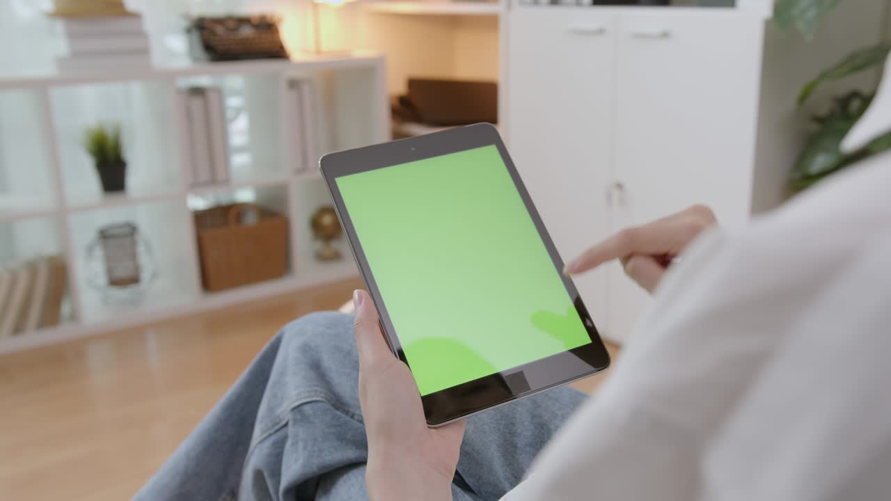 녹색 화면과 터치 장치가 있는 디지털 태블릿을 들고 인터넷을 탐색하는 여성.