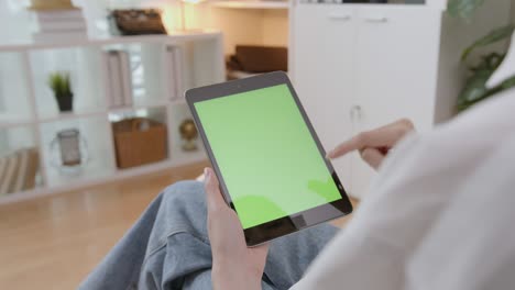 woman holding digital tablet with green screen and touch device browsing internet.