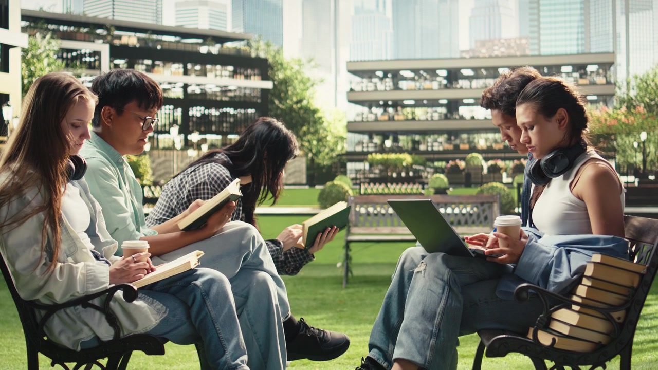 Diverse students reading books and reviewing study materials on campus bench
