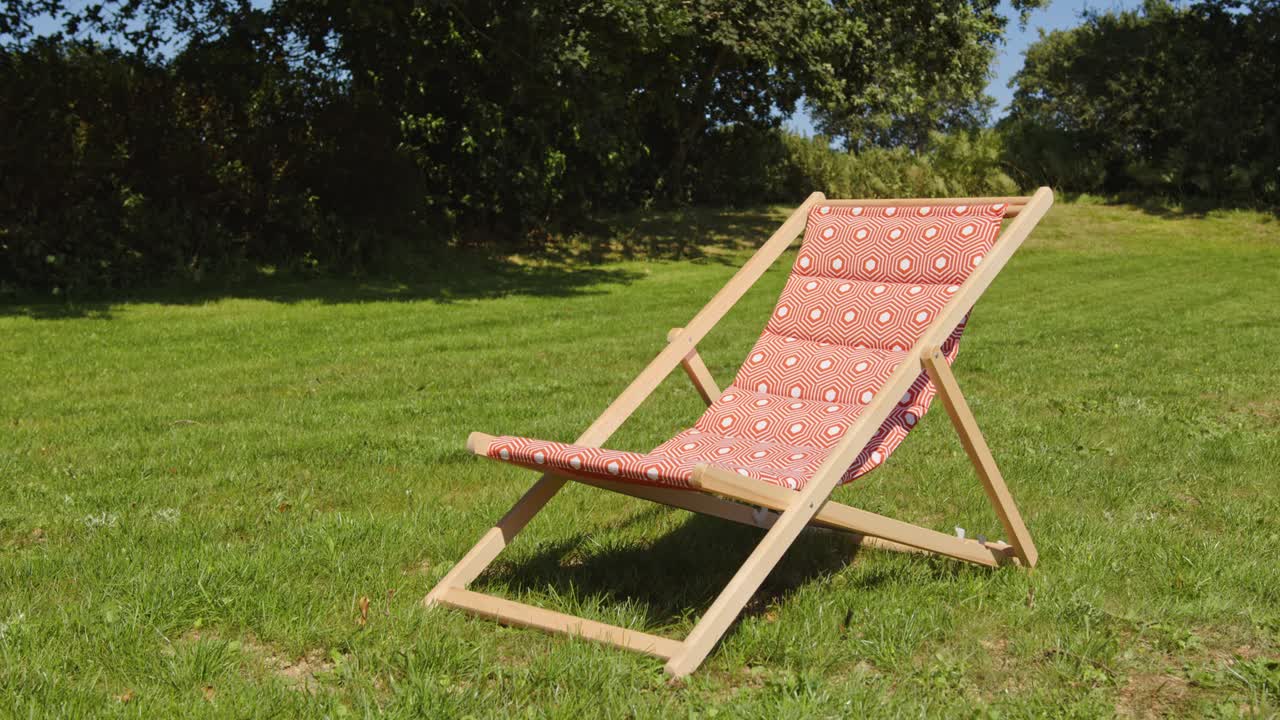 Wooden Deckchair Over Green Lawn On Sunny Day. Static Shot