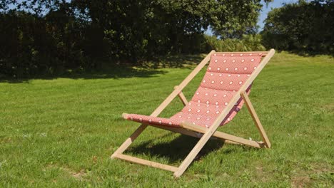 wooden deckchair over green lawn on sunny day. static shot
