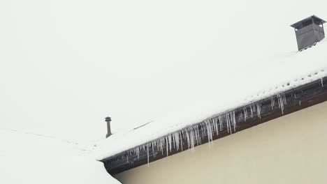 Frozen-house-roof-covered-in-snow,-white-overcast-day-in-winter,-tilt-up