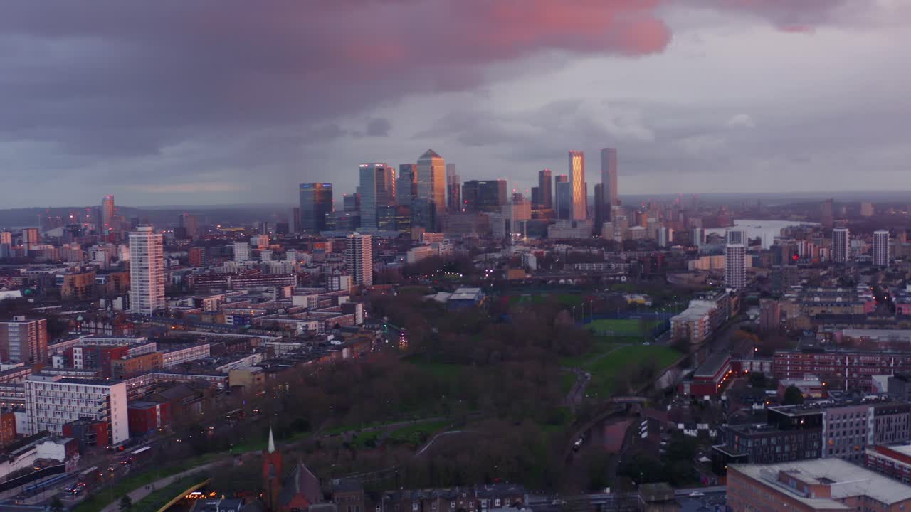 disparo lento de un dron hacia los rascacielos de la torre canary wharf de londres desde el extremo norte de la milla al atardecer