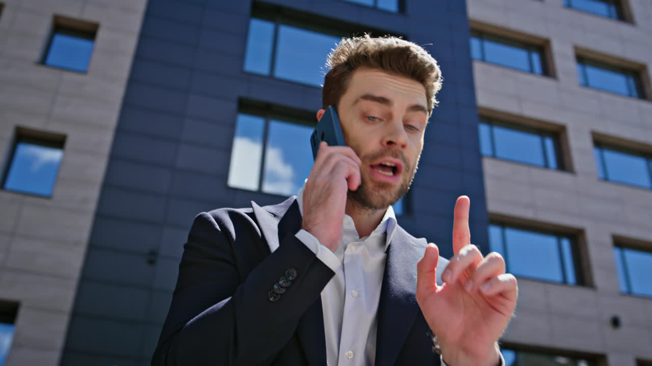 Stressed executive arguing smartphone standing by modern office building closeup