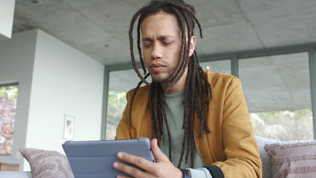 Man adjusting folio tablet case on living room sofa, tapping and swiping to unlock puzzling content