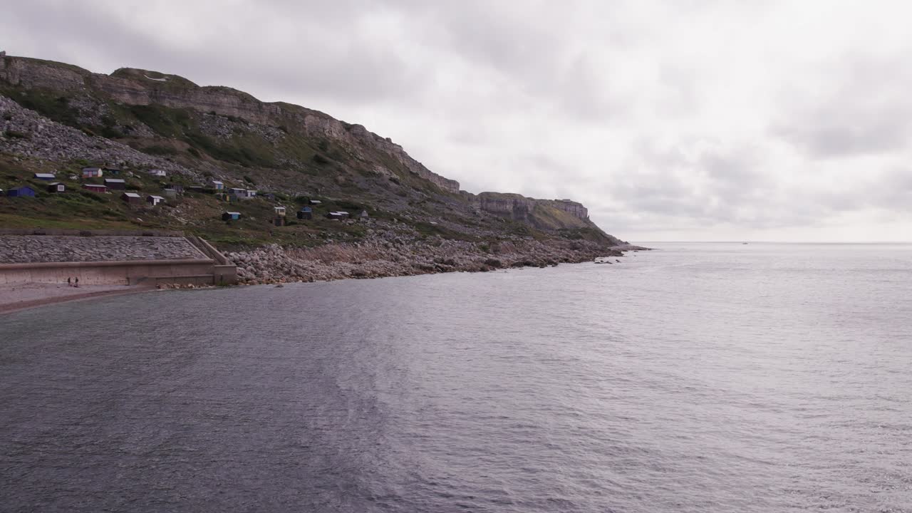 Toma de dron volando hacia arriba en dirección a la Isla de Portland en un día soleado, Weymouth, Dorset, Reino Unido