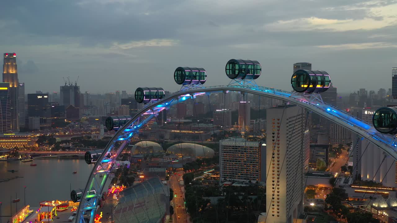 해가 지는 밤에 빛나는 싱가포르 시의 유명한 플라이어 다운타운 공중 파노라마 4k