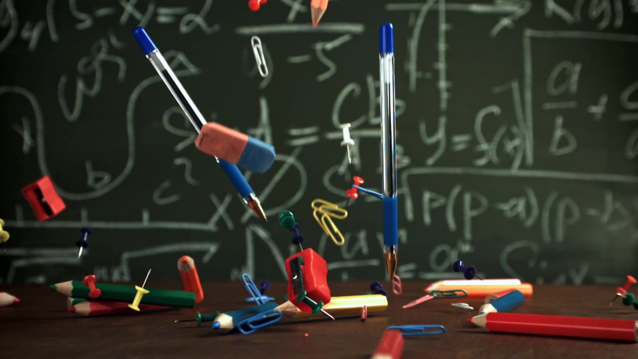 Školní potřeby padající zpomaleně na pozadí matematické tabule.