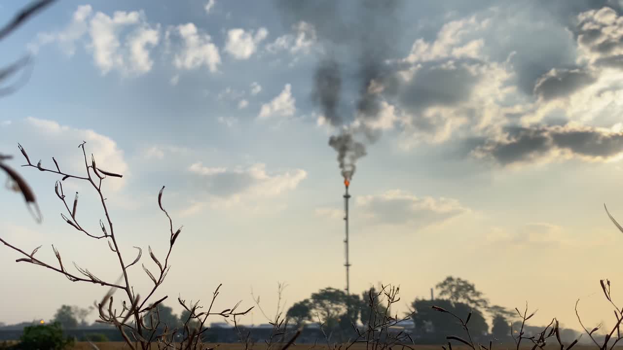 상승하는 샷은 거대한 오염 굴뚝, 시골 전경 풍경을 가진 높은 가스 플레어 정유 산업을 보여줍니다