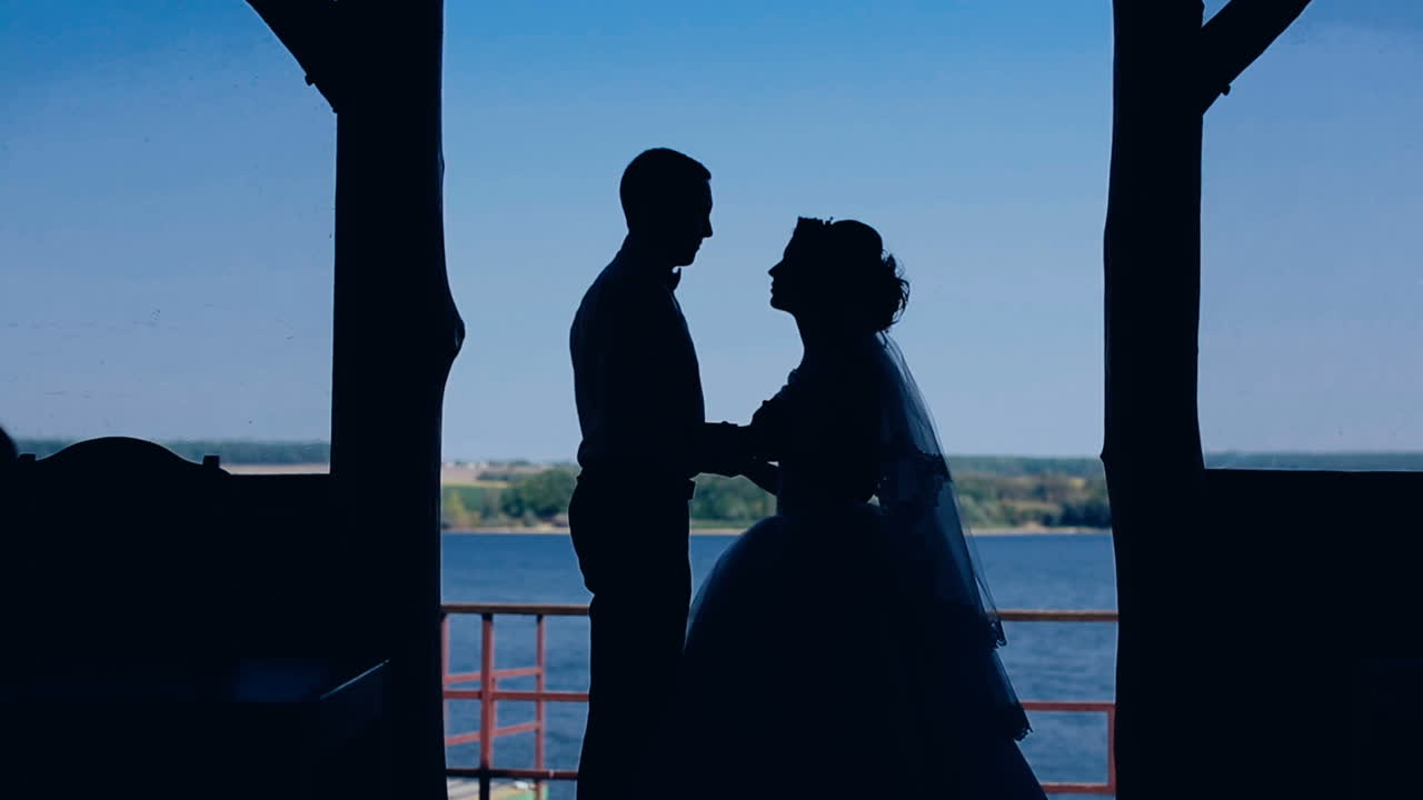 Silhouette of young couple. Silhouettes of wedding couple holding and kissing near lake