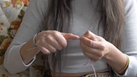 woman in grey shirt knits or crochets a small intricate piece by hand