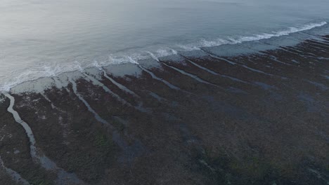 panning drone shot of bingin beach low tide reef at sunset in uluwatu bali indonesia