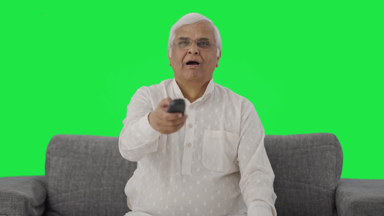 Søvnig indisk ældre mand ser TV og gaber Green screen