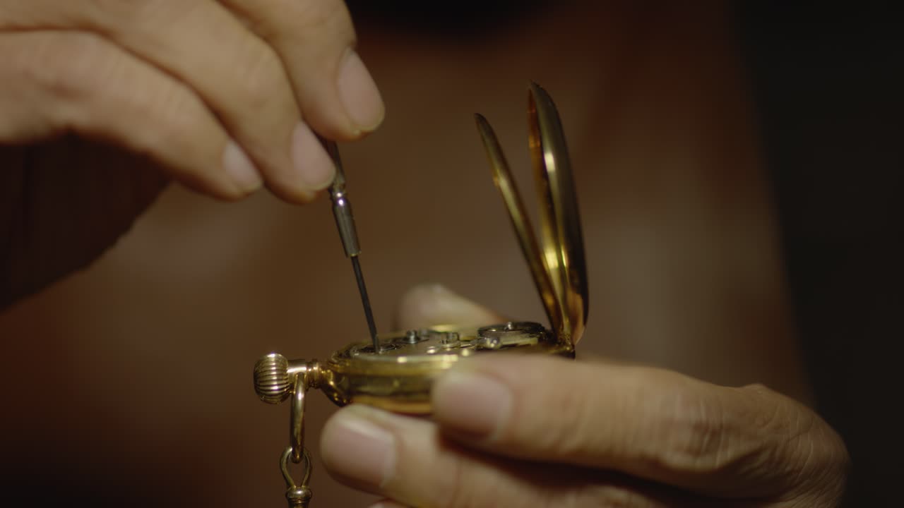 Someone is using a small screwdriver to fix a pocket watch