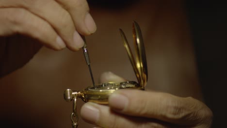 someone is using a small screwdriver to fix a pocket watch