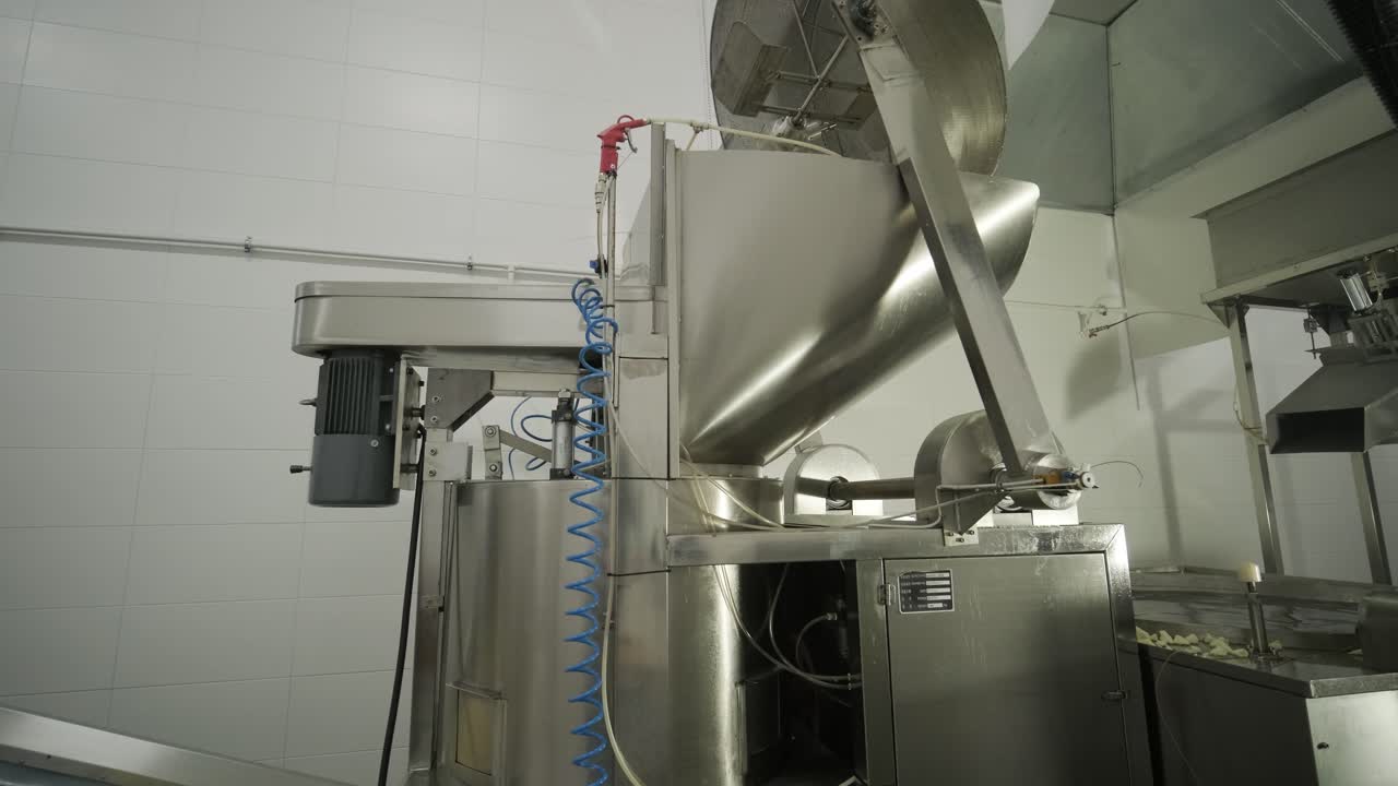producción de papas fritas y bocadillos. máquina industrial de fritura profunda. las papas fritas se fríen en un cuenco grande con aceite. la línea de producción de la fábrica mueve las papas frias doradas después de freír.