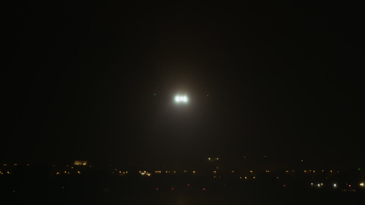 조명된 활주로에 착륙하는 비행기