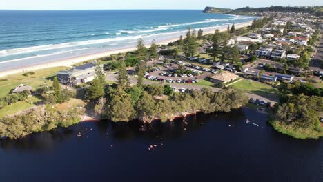 people diving and swimming in lake ainsworth - famous tea tree lake in lennox head, nsw, australia. aerial sideways shot