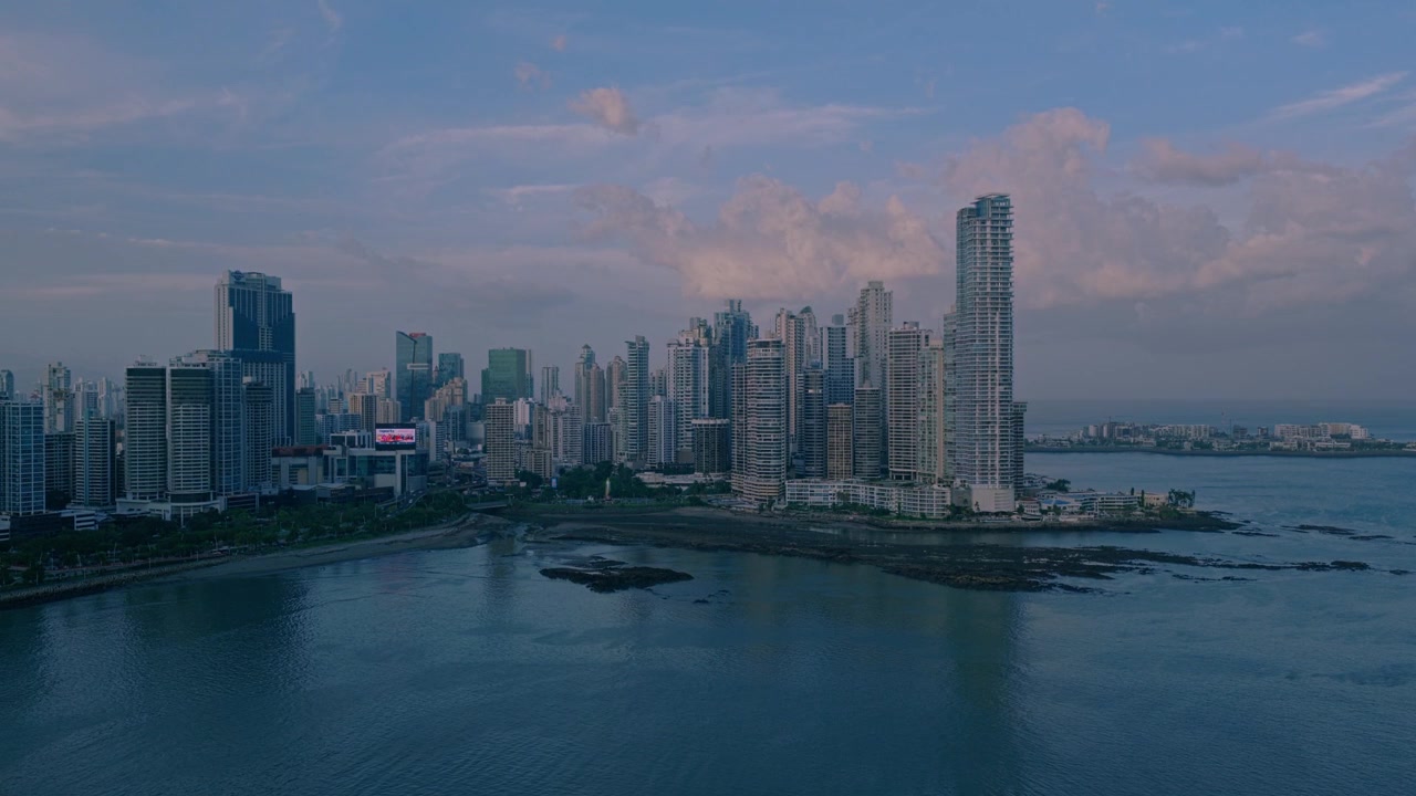Ampia vista aerea dello skyline moderno sul lungomare di Panama City all'alba, con grattacieli, acque costiere calme e soffici nuvole mattutine