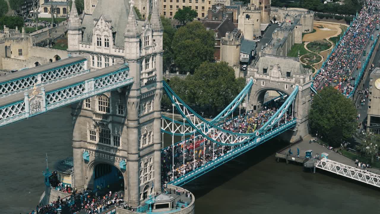 Rightward drone orbit of Tower Bridge with busy crowds and marathon participants