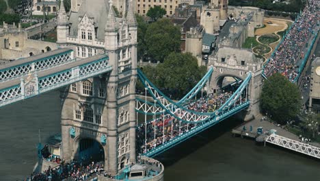 rightward drone orbit of tower bridge with busy crowds and marathon participants