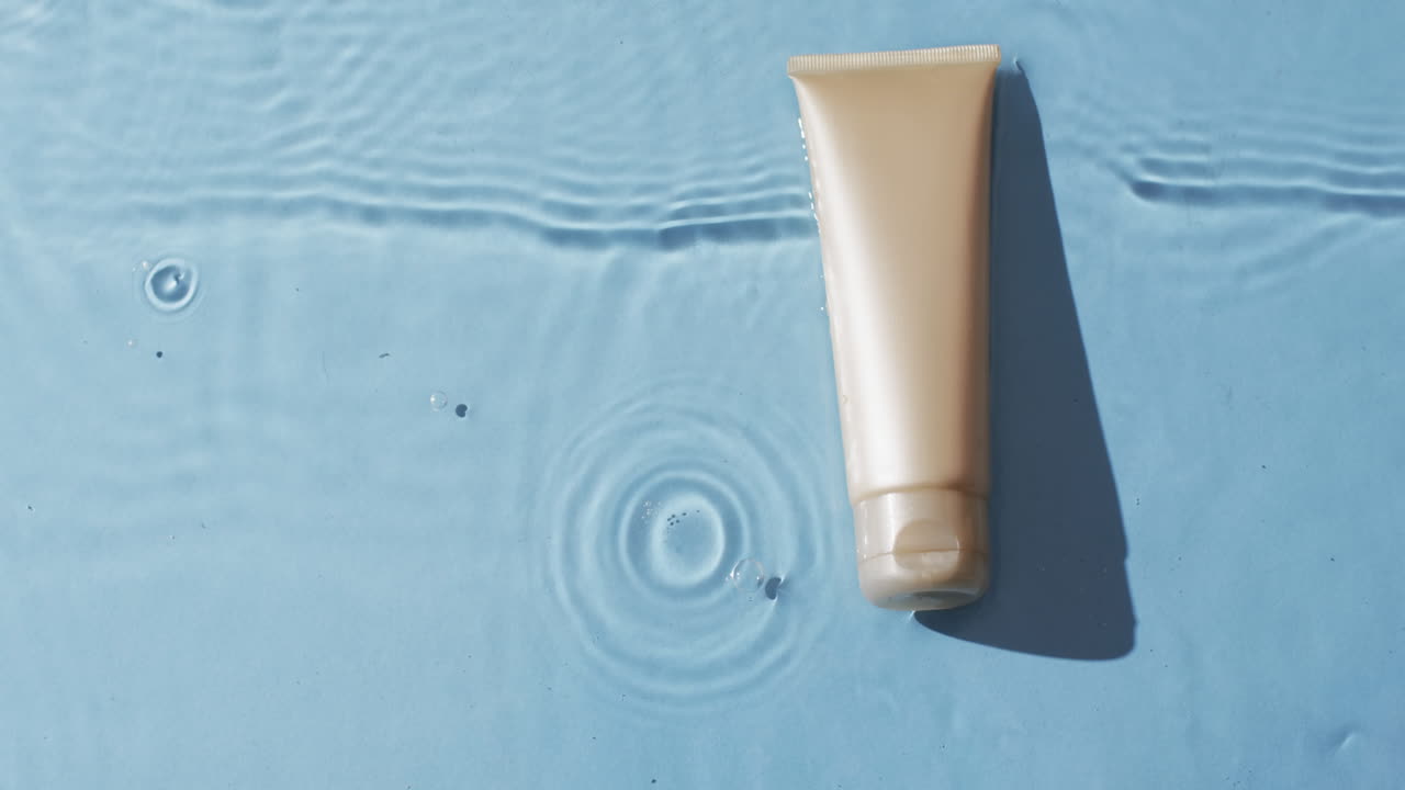 파란색 배경에 복사 공간과 함께 물에 아름다움 제품 튜브의 비디오