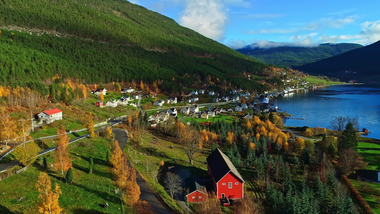 Un pueblo en la ladera de una colina al borde de un fiordo en Noruega durante el otoño - sobrevuelo aéreo