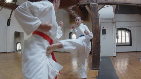 handheld shot of girls practicing karate kicks in gym