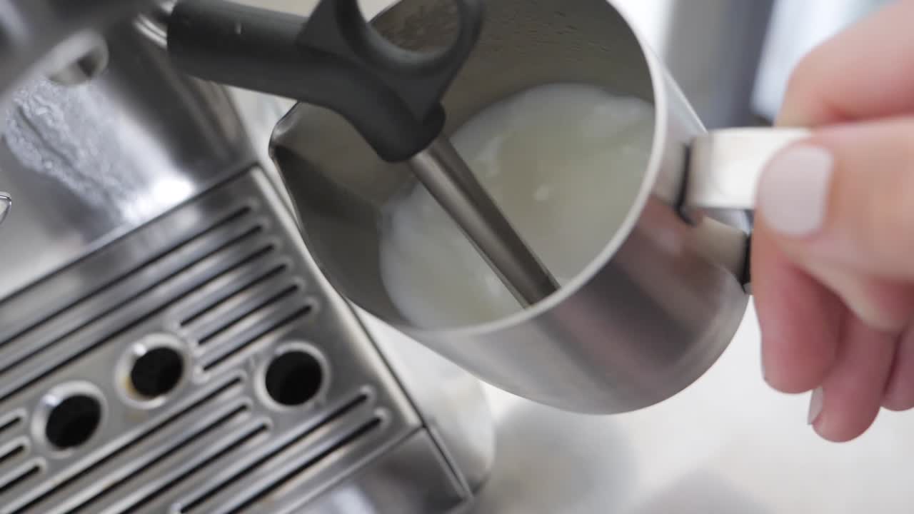 disparo medio de espuma de leche para crear leche al vapor para un latte en una máquina de café espresso de acero inoxidable
