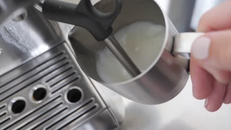 medium shot of milk frothing to create steamed milk for a latte in a stainless steel espresso machine