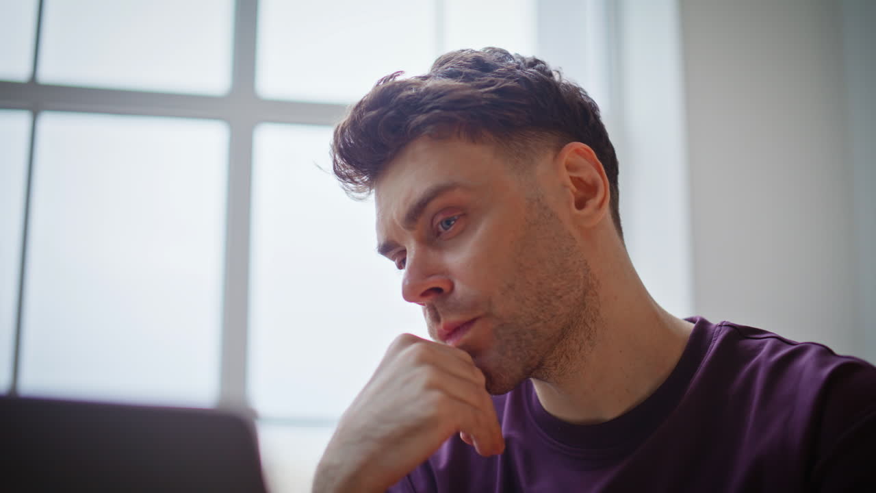 Focused businessman typing laptop working remotely at light apartment closeup