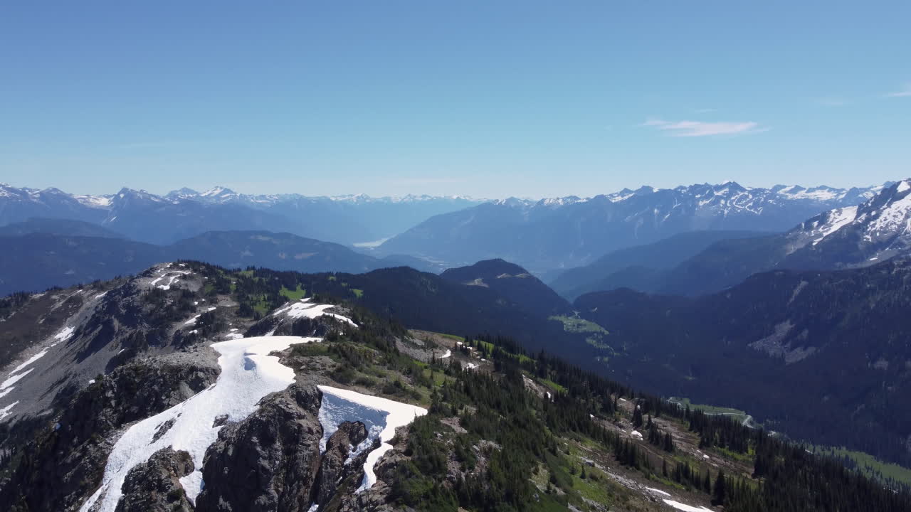 drone aéreo panoramización en paisaje de montaña cubierto de nieve con cielo azul y árboles canadá bc 4k