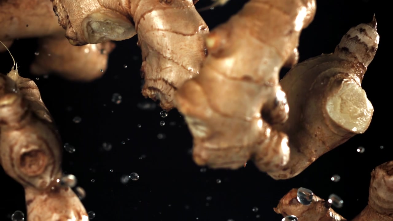 Fresh Ginger Roots Falling with Water Droplets in Slow Motion