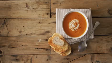 video of cream tomato soup in bowl on wooden table with bread