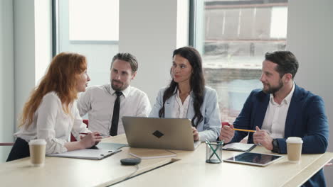 a red-haired businesswoman gives directions to her work team in a business meeting