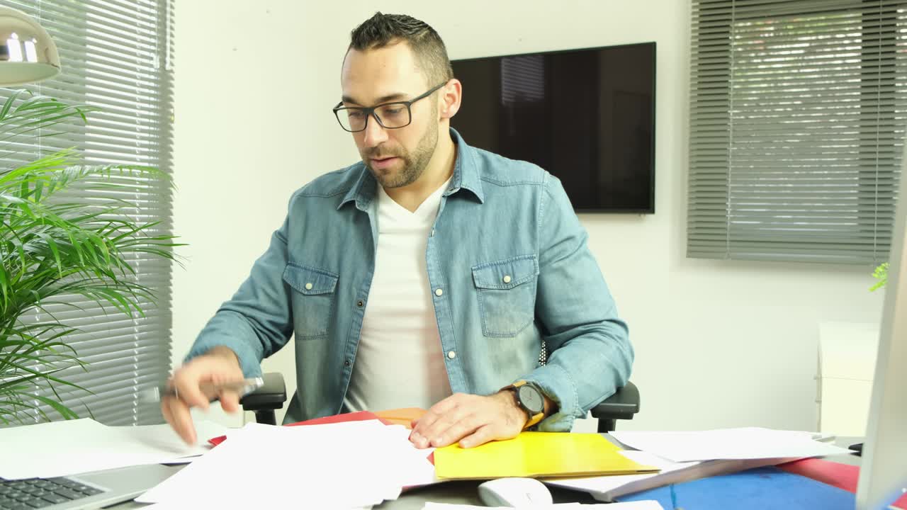 hombre guapo en la oficina ocupado estresado dolor de cabeza papeleo agotamiento