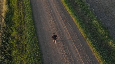 piloto de drones masculino caminando por un camino de tierra en la zona rural de alberta al atardecer