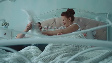 young beautiful couple having fun in bed they fight by cushions laughing slow motion