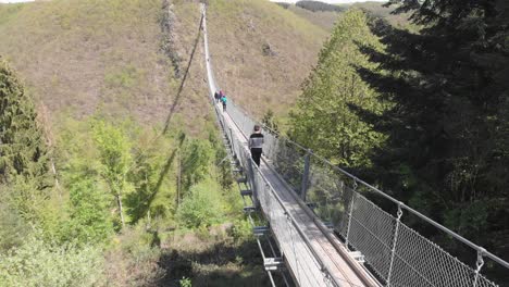 persona cruzando el puente colgante geierlay en el valle del mosela, alemania