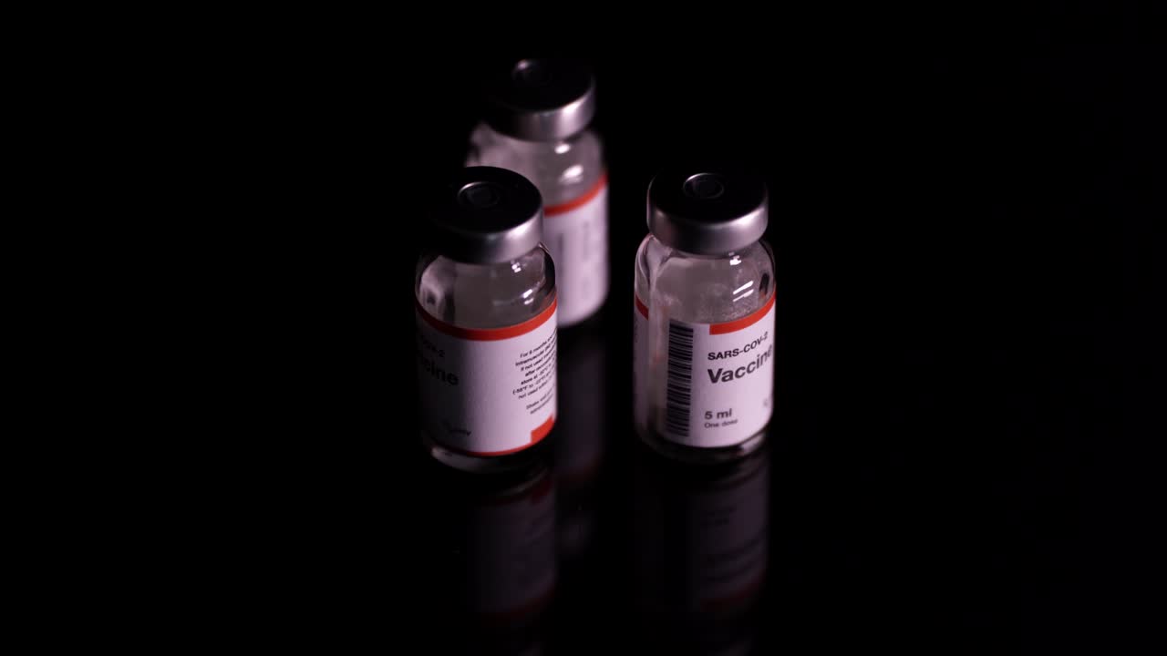 frascos de vacuna covid-19 en plataforma giratoria, aislados en fondo negro