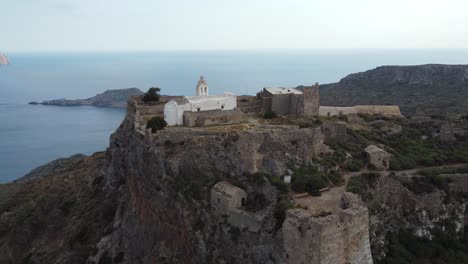 aerial orbital cinematic view over castle of chora kythira revealing kapsáli bay, greece