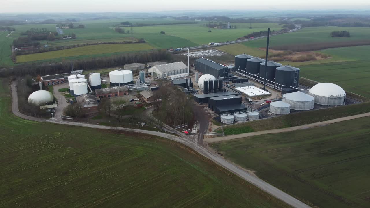 Drone aerial of a biogas plant surrounded by Danish countryside, highlighting renewable energy infrastructure and rural landscape