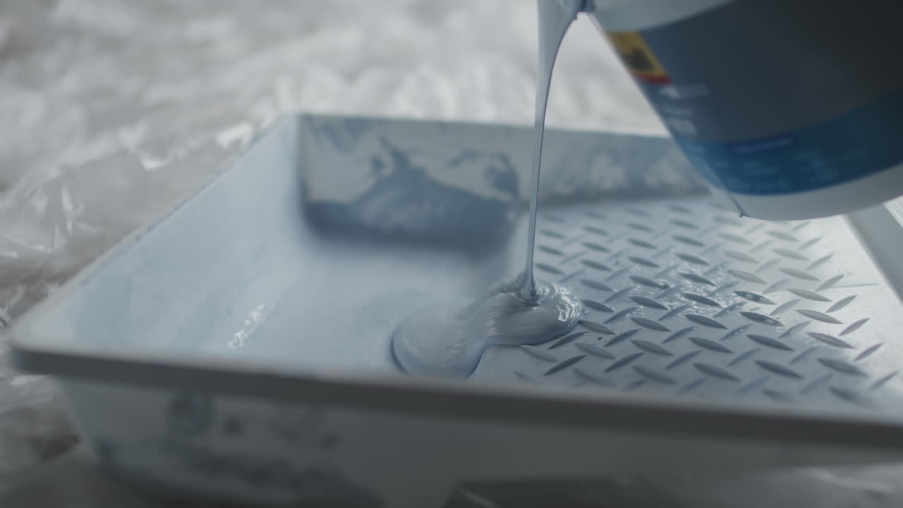 Blue paint pouring into a paint tray