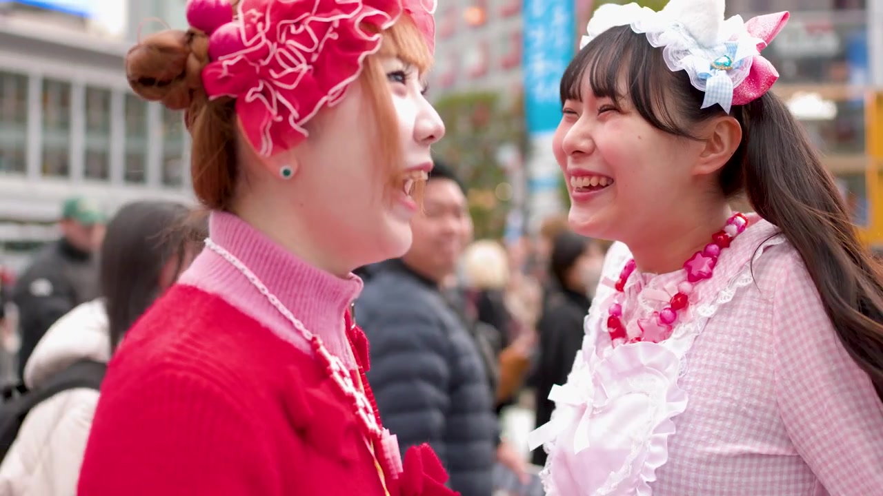 Meninas japonesas com roupas decora coloridas caminham e conversam por uma movimentada faixa de pedestres em Tóquio