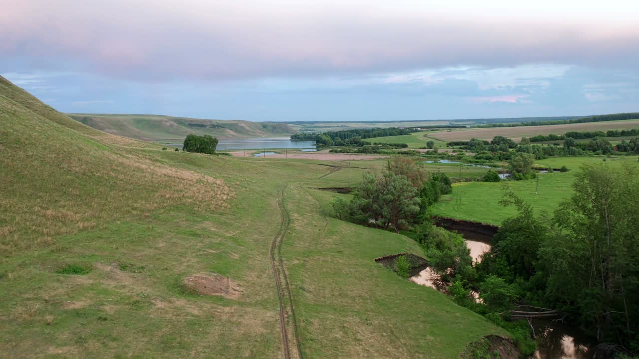 el concepto de senderismo, un viaje a las montañas. el sendero turístico se extiende entre un pintoresco bosque y una montaña de vegetación pored. río sinuoso azul en el fondo.