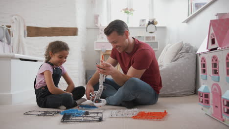 father and daughter in bedroom building robot kit together