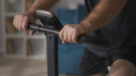 middle-aged man with moustache is training at home on stationary bicycle caring about health and healthy breathing rotating pedals