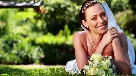 beautiful bride smiling at camera lying on the grass